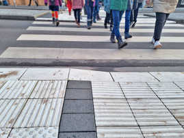 Eine Gruppe Fußgänger, von denen man nur die Beine sieht, überquert einen Zebrastreifen