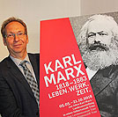 Geschäftsführer Dr. Rainer Auts präsentiert das Plakat für die Trierer Ausstellung zum 200. Geburtstag von Karl Marx.