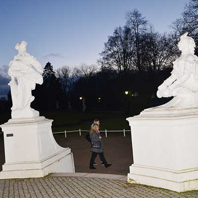Frühabendlicher Blick vom Kurfürstlichen Palais mit den Figuren am Eingang in den Palastgarten. Viele Besucher empfinden die jetzige Beleuchtung der beliebten Grünanlage als unzureichend.