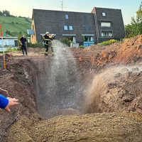 Die Feuerwehr spritzt Wasser auf den Sand, der auf die Bombe geschüttet wurde.