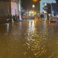 Menschen stehen am Rand einer überschwemmten Straße