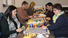 Bei den Kursmaterialien nach dem „Schach für Kids“-Konzept werden im Unterschied zum klassischen Schachspiel Chips und bunte Figuren eingesetzt, um den Kindern den Zugang zu erleichtern. Die Erzieher aus den Kindertagesstätten testen sie bei der Schulung. Foto: Presseamt