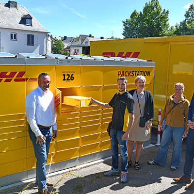 OB Wolfram Leibe und Klimaschutzmanagerin Julia Hollweg freuen sich mit Anke Podewin, Gjejson Fazijaj und Steffen Karsch von der Deutschen Post DHL (v. r.) über die solarbetriebene Packstation, deren Energieversorgung komplett über die Solarpanels auf dem Dach läuft.