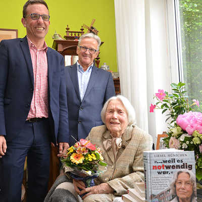 Beigeordneter Thomas Schmitt (l.) und der Heiligkreuzer Ortsvorsteher Theodor Wolber gratulieren Liesel Hünichen zu ihrem 100. Geburtstag. Die Jubilarin hat zahlreiche Bücher verfasst. 